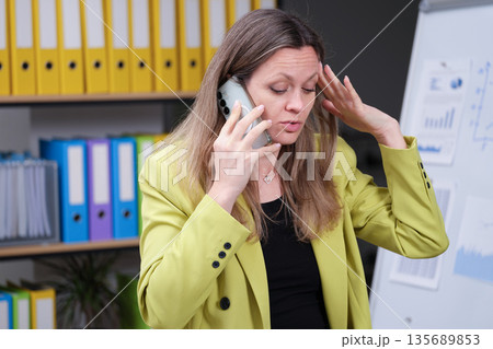 Stressful business call in a modern office environment with colorful folders and charts 135689853