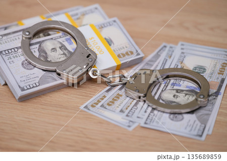 Tension in the air as handcuffs rest on stacks of cash revealing the clash between crime and justice 135689859
