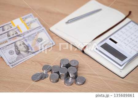 Cash and coins on a workspace with notebook and calculator for budgeting and financial planning Cash and coins on a workspace with notebook and calculator for budgeting and financial planning 135689861