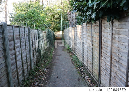 A path is lined with wooden fences and trees A path is lined with wooden fences and trees 135689879