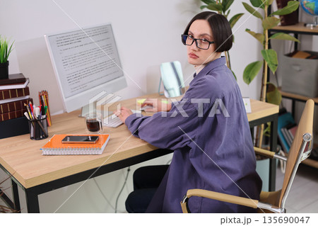 Focused individual types at a modern desk surrounded by greenery in a bright workspace during daytime hours Focused individual types at a modern desk surrounded by greenery in a bright workspace during daytime hours 135690047