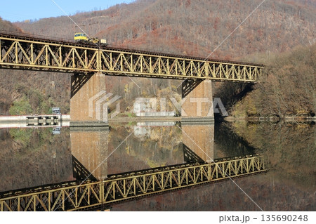 A bridge spans a river with a train crossing it 135690248
