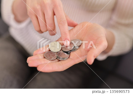 Counting coins with care while sitting comfortably on a soft couch during a calm afternoon 135690573