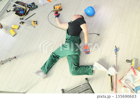Worker rests on the floor surrounded by tools after a long day of renovation in a bright, modern space 135690683