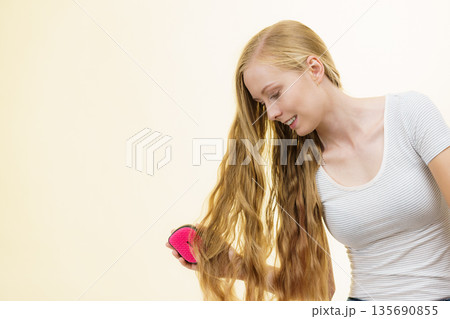 Blonde girl brushing her long hair Blonde girl brushing her long hair 135690855