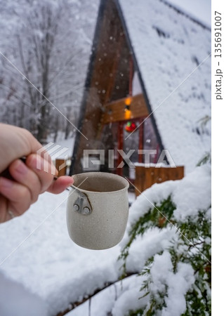 Hand Holding Coffee Pot with A-Frame House Hand Holding Coffee Pot with A-Frame House 135691007