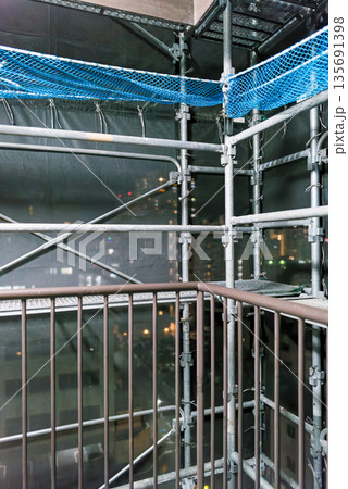 マンション外壁補修の足場　夜景が透けるメッシュシート　工事現場の背景素材 135691398
