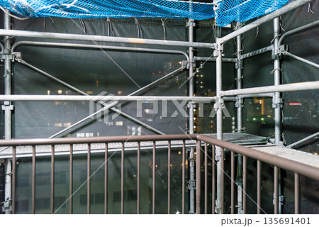 マンション外壁補修の足場 夜景が透けるメッシュシート 工事現場の背景素材 マンション外壁補修の足場 夜景が透けるメッシュシート 工事現場の背景素材 135691401