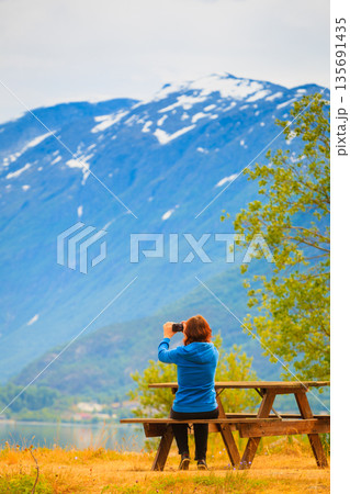 Tourist taking photo at norwegian fjord Tourist taking photo at norwegian fjord 135691435