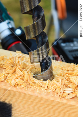 Metal machine drilling in wooden board 135691542