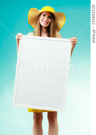 Woman in bikini holds blank presentation board. Woman in bikini holds blank presentation board. 135692520