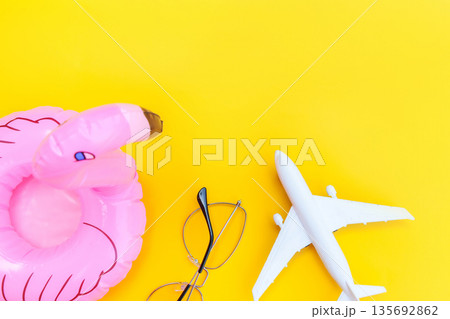 Summer beach composition. Minimal simple flat lay with plane sunglasses and Inflatable flamingo isolated on yellow background. Vacation travel adventure trip concept. Top view copy space Summer beach composition. Minimal simple flat lay with plane sunglasses and Inflatable flamingo isolated on yellow background. Vacation travel adventure trip concept. Top view copy space 135692862