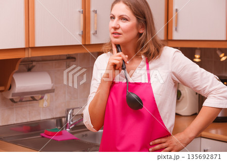 Housewife with ladle in kitchen Housewife with ladle in kitchen 135692871