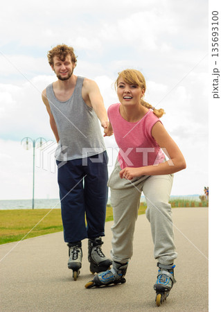 Woman encourage man to do rollerblading Woman encourage man to do rollerblading 135693100