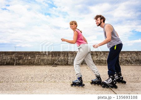 Two people race together riding rollerblades. 135693108