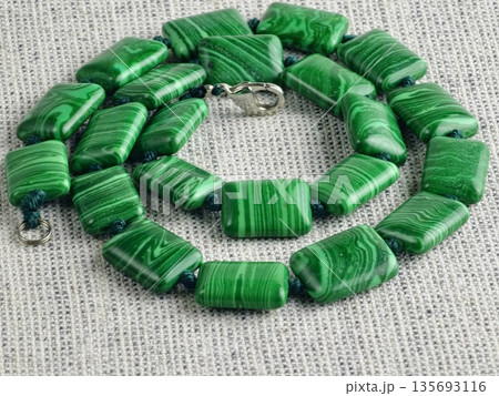 Close-up of green malachite rectangular bead necklace on a burlap background Close-up of green malachite rectangular bead necklace on a burlap background 135693116