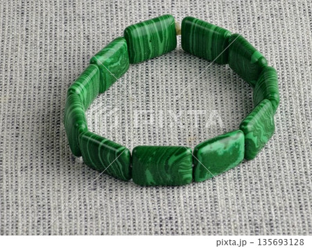 Close-up of green malachite rectangular bead bracelet on burlap background Close-up of green malachite rectangular bead bracelet on burlap background 135693128