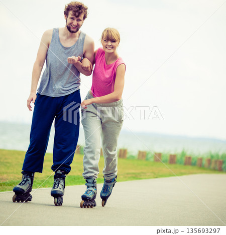 Young couple holding hands while rollerblading Young couple holding hands while rollerblading 135693297
