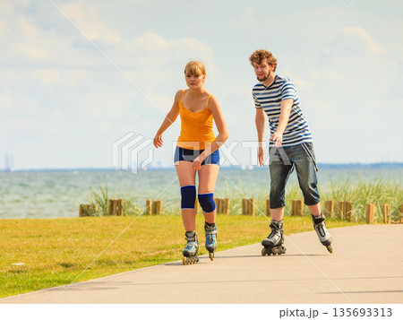 Young couple on roller skates riding outdoors 135693313