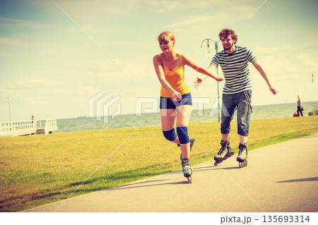 Young couple on roller skates riding outdoors Young couple on roller skates riding outdoors 135693314