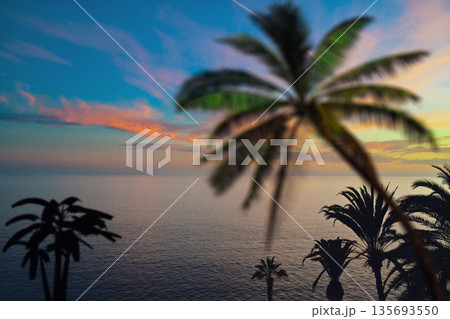 Dramatic golden sunset over a calm ocean with sunbeams and storm clouds. 135693550