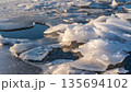 Frozen cracked lake ice with layers of transparent and white chunks 135694102