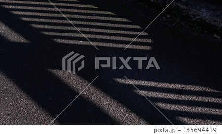 アスファルトに落ちた柵の影 アスファルトに落ちた柵の影 135694419