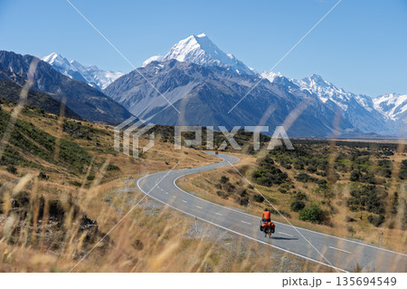 Cyclist riding winding S-curve road toward Mount Cook, New Zealand 135694549