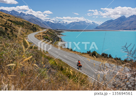 Cyclist riding scenic road along Lake Pukaki toward Mount Cook, New Zealand Cyclist riding scenic road along Lake Pukaki toward Mount Cook, New Zealand 135694561