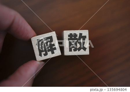 解散を象徴する木製ブロックと暗色の木目背景。 135694804