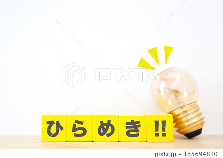 ひらめきを象徴する電球と黄色の木製ブロック。 135694810