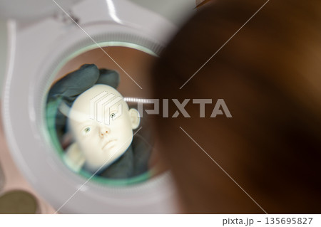 Artist examining ball jointed doll head under Artist examining ball jointed doll head under 135695827