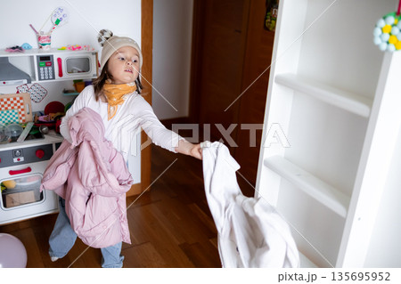 Young caucasian female child playing with jackets at home 135695952
