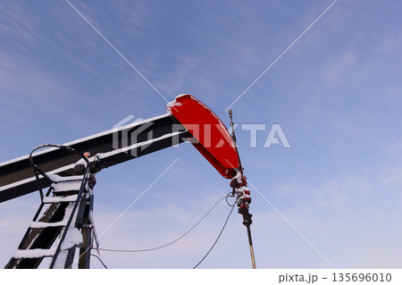 Oil Pumpjack's horsehead against blue and pink sky. Oil Pumpjack's horsehead against blue and pink sky. 135696010
