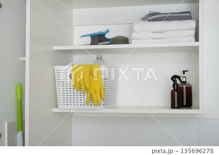 Cleaning supplies and towels organized in cupboard 135696278