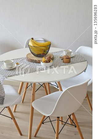 Modern dining table with fruit basket and tea cups 135696283