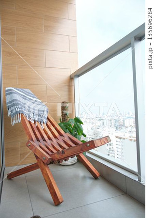 Cozy balcony with wooden chair and city skyline view Cozy balcony with wooden chair and city skyline view 135696284