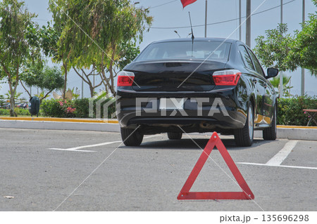 Black sedan having breakdown with warning triangle in parking lot 135696298