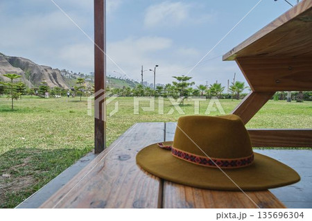 Felt hat resting on wooden picnic table in park 135696304
