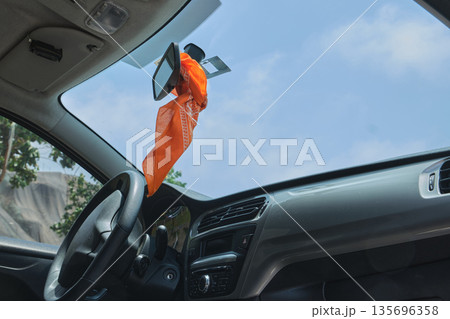 Orange bandana hanging from car rear view mirror Orange bandana hanging from car rear view mirror 135696358