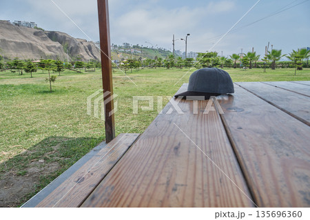 Cap sitting on wooden picnic table in park Cap sitting on wooden picnic table in park 135696360