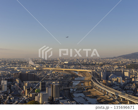 朝日に照らされた都市と青空を飛ぶ飛行機 朝日に照らされた都市と青空を飛ぶ飛行機 135696671
