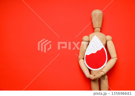 Wooden mannequin with blood drop symbol on red backdrop 135696681