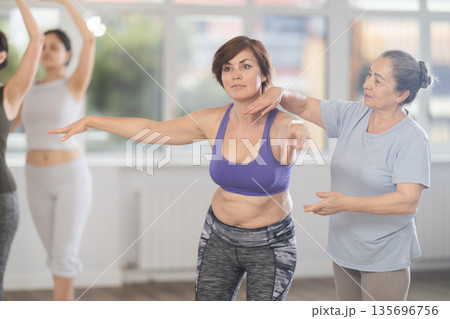 Elderly woman teacher correcting female dancers Elderly woman teacher correcting female dancers 135696756