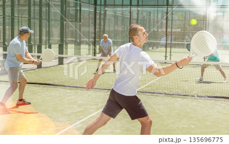 Adult and young men playing padel against two men Adult and young men playing padel against two men 135696775