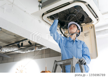 エアコンの点検をする女性作業員 135696789