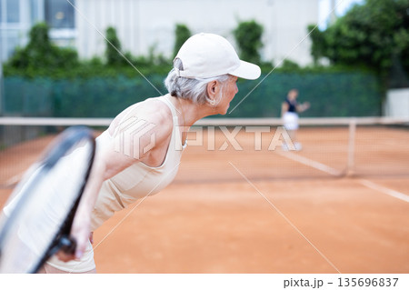 Elderly woman plays tennis on tennis court Elderly woman plays tennis on tennis court 135696837
