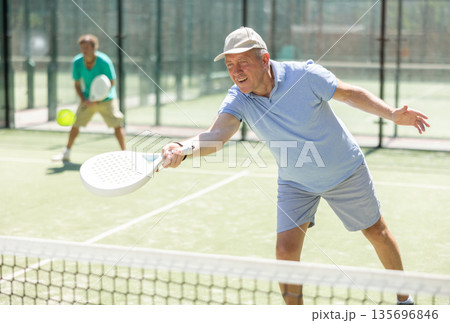 Elderly and adult men playing doubles padel Elderly and adult men playing doubles padel 135696846