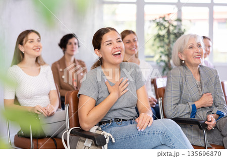 Young positive woman listening to lecture in office Young positive woman listening to lecture in office 135696870