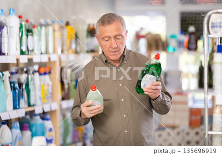 Elderly male customer diligently picking out dishwashing liquid 135696919